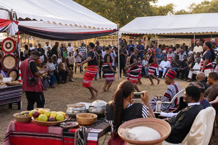 An Idoma community celebration in Abuja with colourful attire, canopies, food displays, dancers and families gathered outdoors.